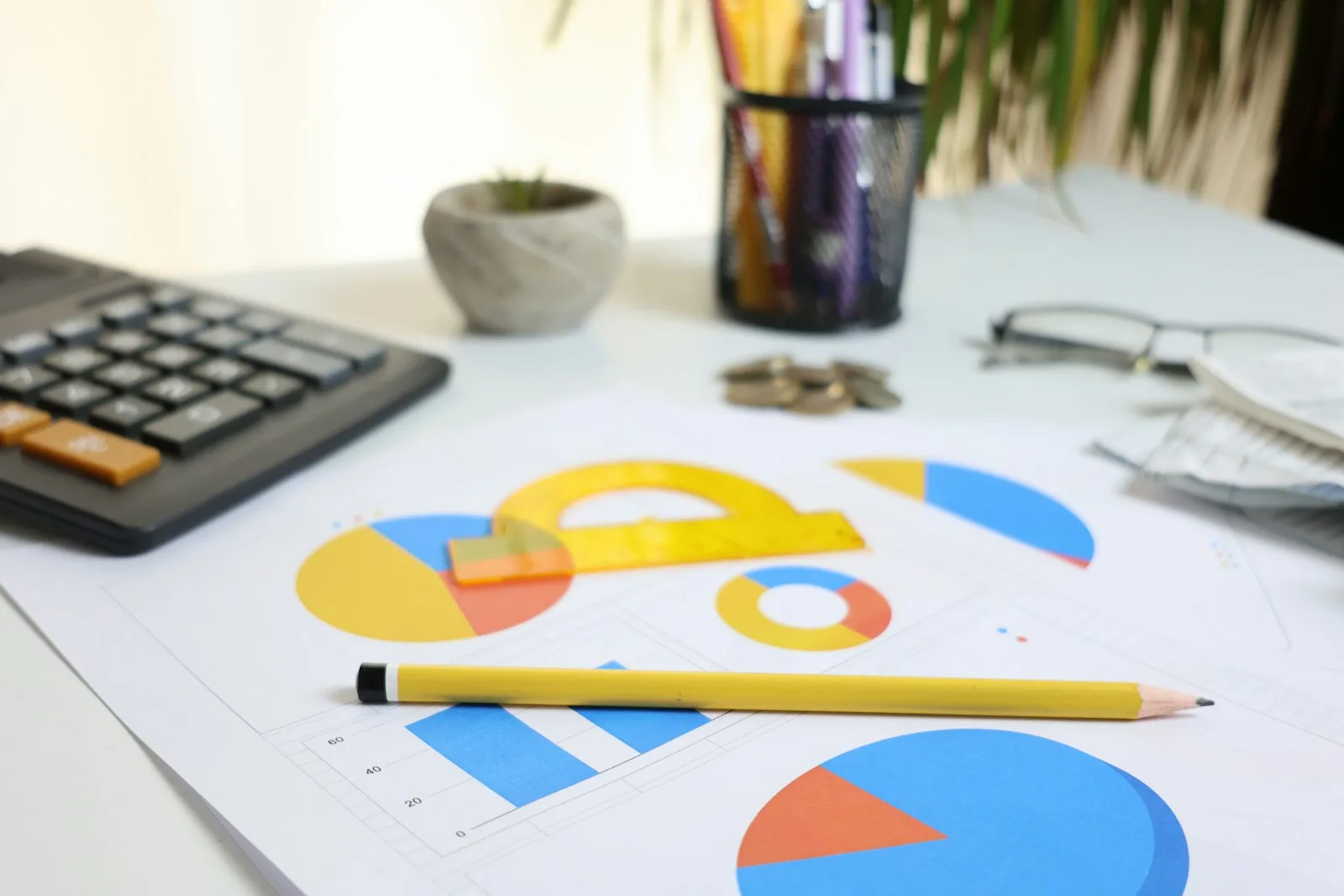 Mesa de trabajo con una calculadora, gráficas impresas y un lápiz