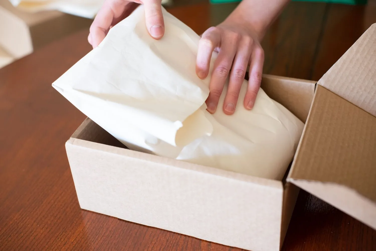 Manos preparando el envío de un pedido en una caja de cartón